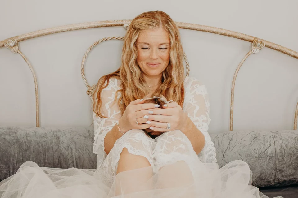 Mother sitting on a bed holding her baby in her legs