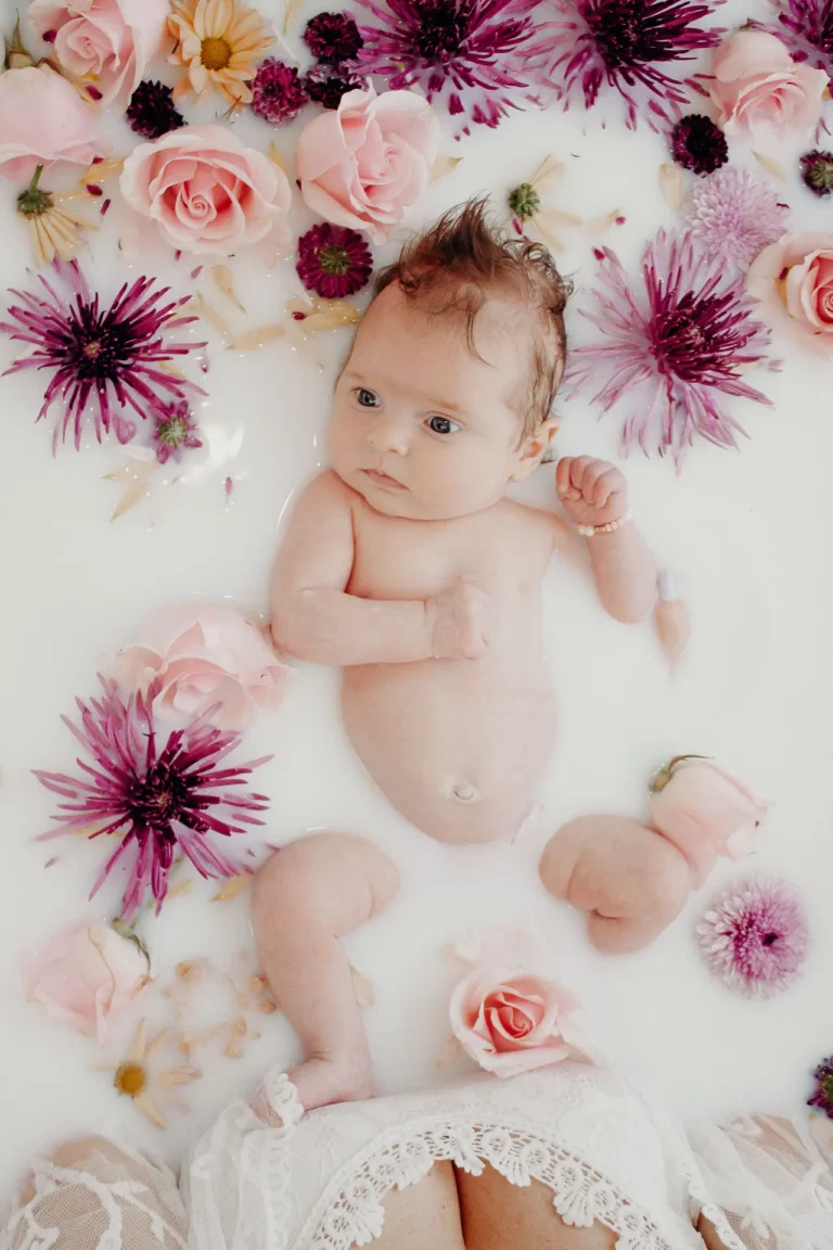 Baby being held in a milk bath full of flowers