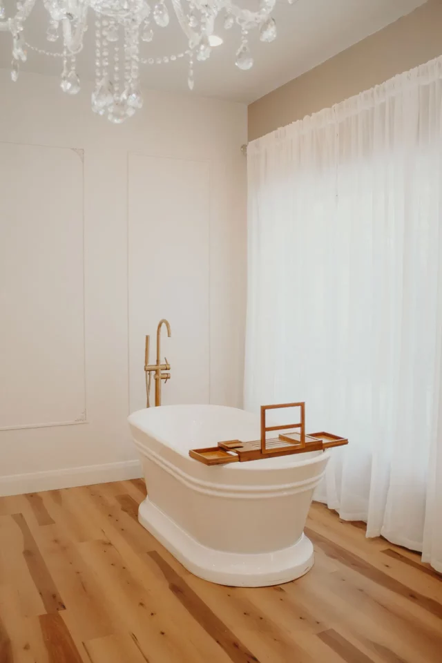 Functional stand alone, white bath tub with tall gold faucet